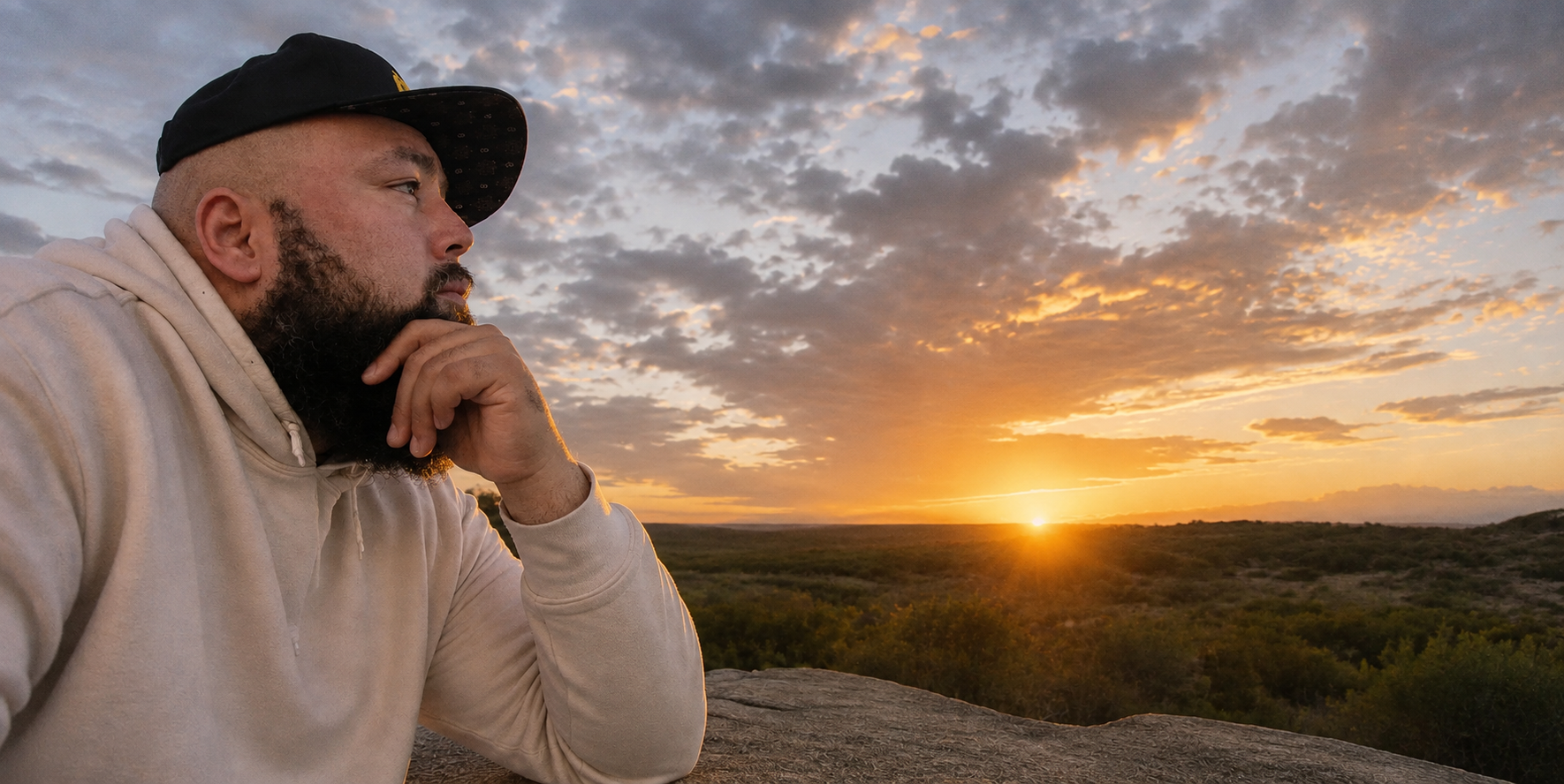 Mark A. Evans sitting on a rock outdoors at sunset, looking out over the landscape